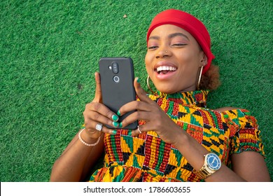 A Beautiful African Lady Laying On The Floor In A Park Using Her Mobile Phone