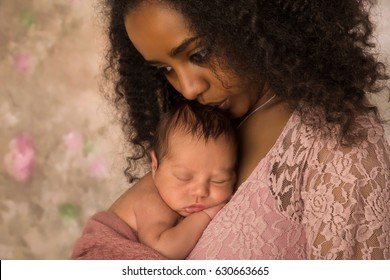 Beautiful African mother in pink lace dress holding her 1 week old little baby
