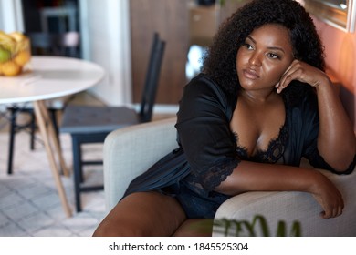 beautiful african plus size model sits on chair at home, have rest in the morning, in contemplation. black fat woman in underwear, domestic wear - Powered by Shutterstock