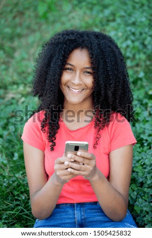 Beautiful african teenager girl with a mobile in a park