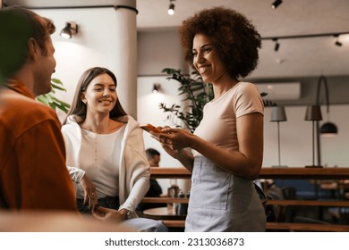 Beautiful african waitress wearing apron smiling while taking order in cafe - Powered by Shutterstock