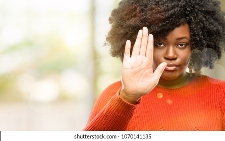 Beautiful african woman annoyed with bad attitude making stop sign with hand, saying no, expressing security, defense or restriction, maybe pushing, outdoor - Shutterstock ID 1070141135