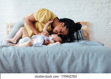 Beautiful African Woman Cuddling Her Baby Daughter In Bedroom.