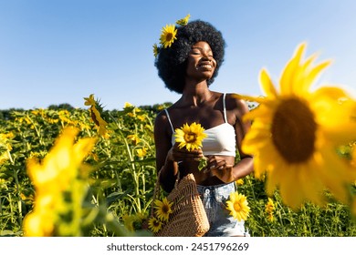 Beautiful african woman with curly afro style hair in a sunflowers field - Powered by Shutterstock