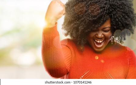 Beautiful african woman happy and excited expressing winning gesture. Successful and celebrating victory, triumphant, outdoor - Shutterstock ID 1070141246