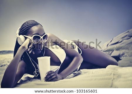 Beautiful african woman lying on a beach and having a refreshing drink