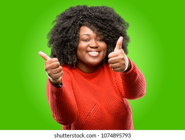 Beautiful african woman stand happy and positive with thumbs up approving with a big smile expressing okay gesture