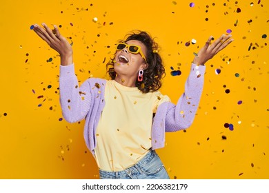 Beautiful African Woman Throwing Confetti And Smiling Against Yellow Background