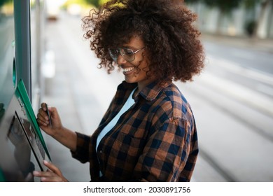 Beautiful African woman using ATM machine. Attractive young woman withdrawing money from credit card at ATM.