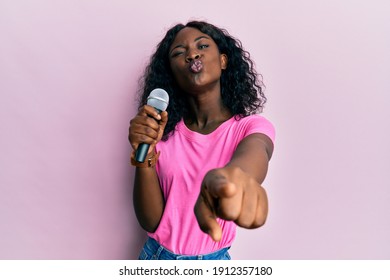 Beautiful African Young Woman Singing Song Using Microphone Pointing To Camera Looking At The Camera Blowing A Kiss Being Lovely And Sexy. Love Expression. 