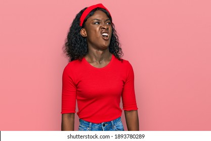 Beautiful african young woman wearing casual clothes angry and mad screaming frustrated and furious, shouting with anger. rage and aggressive concept.  - Shutterstock ID 1893780289