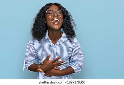 Beautiful african young woman wearing casual clothes and glasses smiling and laughing hard out loud because funny crazy joke with hands on body. 