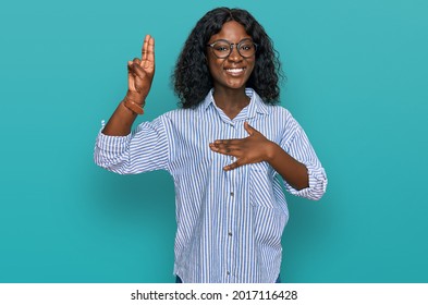 Beautiful african young woman wearing casual clothes and glasses smiling swearing with hand on chest and fingers up, making a loyalty promise oath 