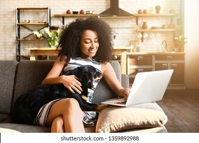 Beautiful African-American Woman With Cute Dog Working On Laptop At Home