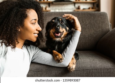 Beautiful African-American woman with cute dog at home