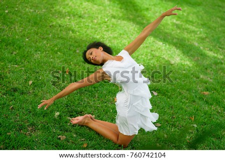 A beautiful African-looking girl with black short hair in a dancing pose dressed in a white dress