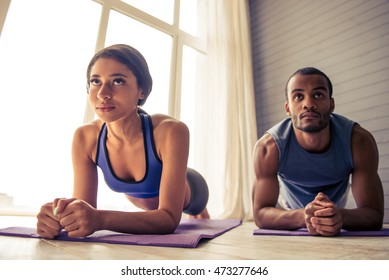 Beautiful Afro American Couple In Sports Clothes Is Doing Plank On Yoga Mat While Working Out At Home