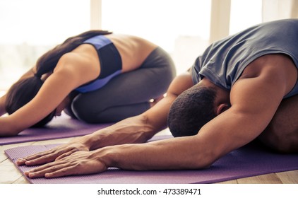 Beautiful Afro American couple in sports clothes is stretching on yoga mat while working out at home - Powered by Shutterstock