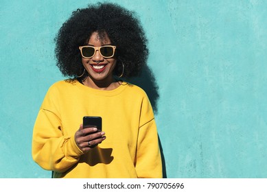 Beautiful afro american woman using mobile in the street. Communication concept.