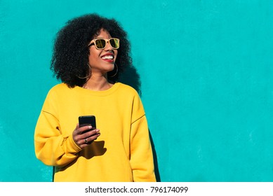Schöne Afro-Amerikanerin mit Handy auf der Straße. Kommunikationskonzept.