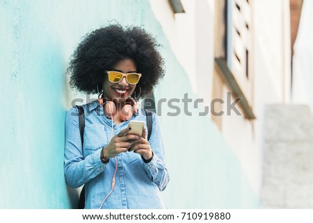 Similar – Frau mit Afro-Haaren auf der Straße, die ein Smartphone hält.