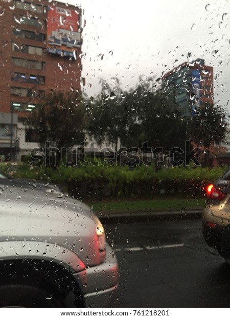 beautiful afternoon storm background fall\
autumn winter with small close up on raindrops falling in a clear\
window with cars traffic street on the back\
