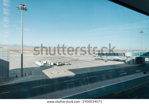 Beautiful airport with\
cars, a boarding bridge and an empty runway against the backdrop of\
mountains, desert and blue sky. Travel by plane concept. Pandemic\
and airlines