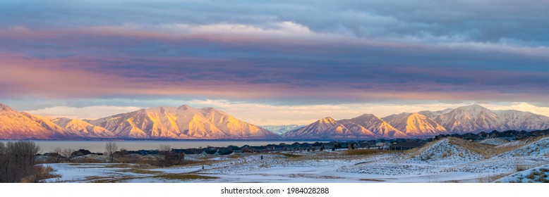 Beautiful alpenglow view of Mount Timpanogos Wasatch mountains at Saratoga Springs, Utah. There is a snowy field and houses against the lake and mountain view with pink orange reflection at the back. - Powered by Shutterstock