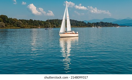 Beautiful alpine summer view with a sailboat, reflections and the alps in the background at the famous Chiemsee, Bavaria, Germany