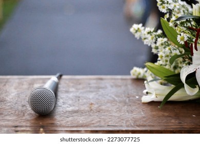 a beautiful altar table from a wedding with a microphone on top and an arrangement of white flowers on the side