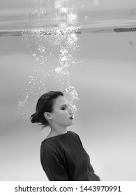 Beautiful Amazing Stylish Pretty Young Woman In Green Dress, Red Gloves, Black Clutch Bag And Tights In The Net Underwater In The Swimming Pool. Fashion And Shopping Concept