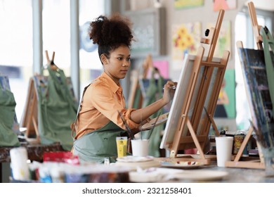 Beautiful american african artist woman painting in art studio at the university classroom - Powered by Shutterstock