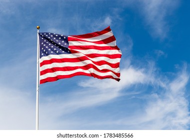 Beautiful American flag waving in the wind, with vibrant red white and blue colors against blue sky, with copy space.