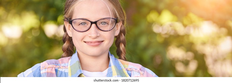 Beautiful American Portrait Of Schoolgirl. Preschool Kid. Little Happy Girl Outdoors. Pretty Female Person. Adorable Candid Children. Green Park. Staycation. Nerd Teen. Idea. Looking At Camera.