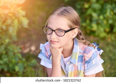 Beautiful American Portrait Of Schoolgirl. Preschool Kid. Little Happy Girl Outdoors. Pretty Female Person. Adorable Candid Children. Green Park. Staycation. Nerd Teen. Idea. Looking At Camera.