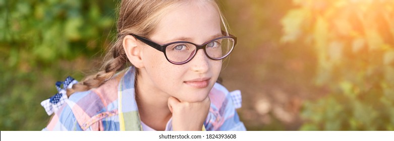 Beautiful American Portrait Of Schoolgirl. Preschool Kid. Little Happy Girl Outdoors. Pretty Female Person. Adorable Candid Children. Green Park. Staycation. Nerd Teen. Idea. Looking At Camera.