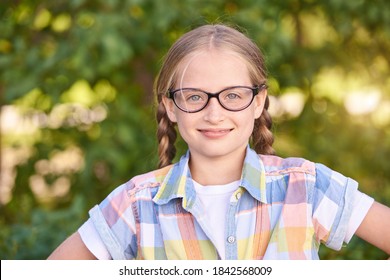 Beautiful American Portrait Of Schoolgirl. Preschool Kid. Little Happy Girl Outdoors. Pretty Female Person. Adorable Candid Children. Green Park. Staycation. Nerd Teen. Idea. Looking At Camera