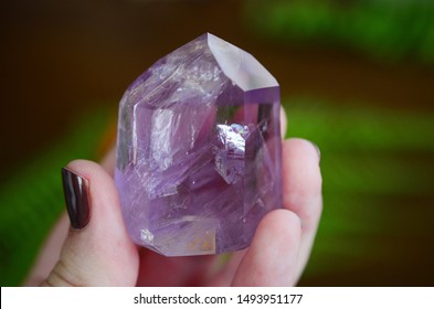 Beautiful Amethyst tower, lots of rainbows. Beautiful polished amethyst tower. Bright Quartz crystal, healing crystal being held in hand. Woman holding amethyst tower, natural lighting, reiki energy