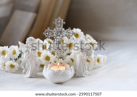 Beautiful angel figurines, burning candle, decorative openwork cross and flowers on table. symbol of Christianity religion, faith in God, prayer, memory. christian home altar.