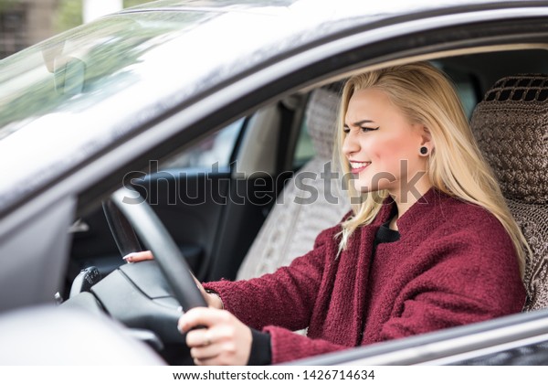 Beautiful
angry woman honking in her car while
driving