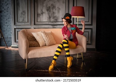 A beautiful animator or cabaret girl in a costume of a ringmaster (entertainer) of an old circus: a red striped tailcoat, a bowler hat, a striped black and yellow tights. Vintage steampunk style