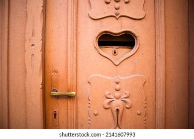 Beautiful antique terracotta door decorated with carvings and postal mail slot. Letter box in shape of heart with key hole. Valentine's day concept. Mailbox for love letters. Feeling love background.