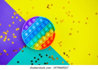 beautiful anti-stress sensory toy fidget push pop it on multicolored with stars confetti background