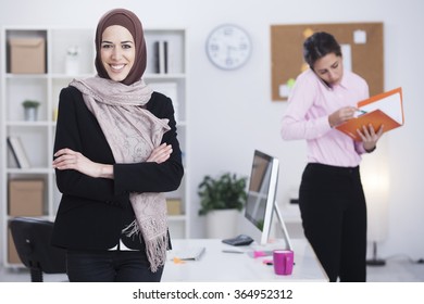 Beautiful Arabic Business Woman Working In Her Office With Her Worker In Blur. Two Business Women,Shallow Depth Of Field