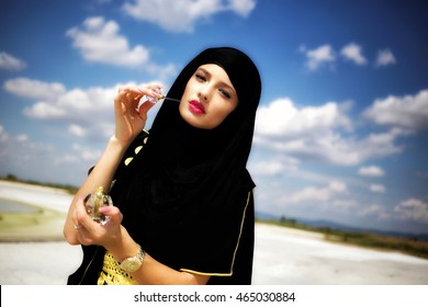 Beautiful Arabic girl portrait at sunset. Beauty young Arabian woman with menhdi, perfect make-up and accessories hiding her face behind a veil. Indian Bride. Arab Traditions and culture concept.