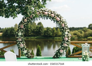 Beautiful arch for wedding ceremony, natural background of trees and lake, wedding decor