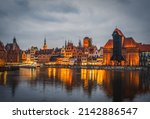 Beautiful architecture of the old town in Gdansk by the Motlawa river with a historic port crane at night. Poland, November 2021