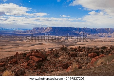 A beautiful Arizona desert red rock landscape on a sunny and hot summer day with a plateau mountain range in the distance with a blue sky seperating the skyline. 