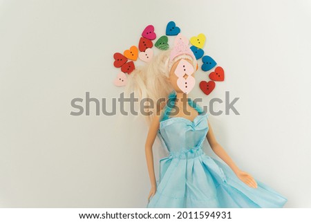 Beautiful arrangement of doll in blue dress and bunch of colorful hearts