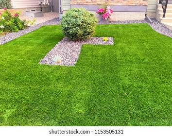 A beautiful artificial lawn in the front yard with nice flowers and shrubs surrounding it